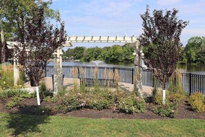 A garden with a pergola, a body of water, and a bridge.
