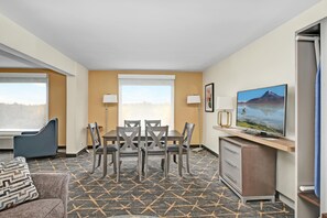 A hotel room with a dining table, chairs, a TV, a sofa, and a view of a mountain. - Holiday Inn Piscataway - Somerset (Piscataway)