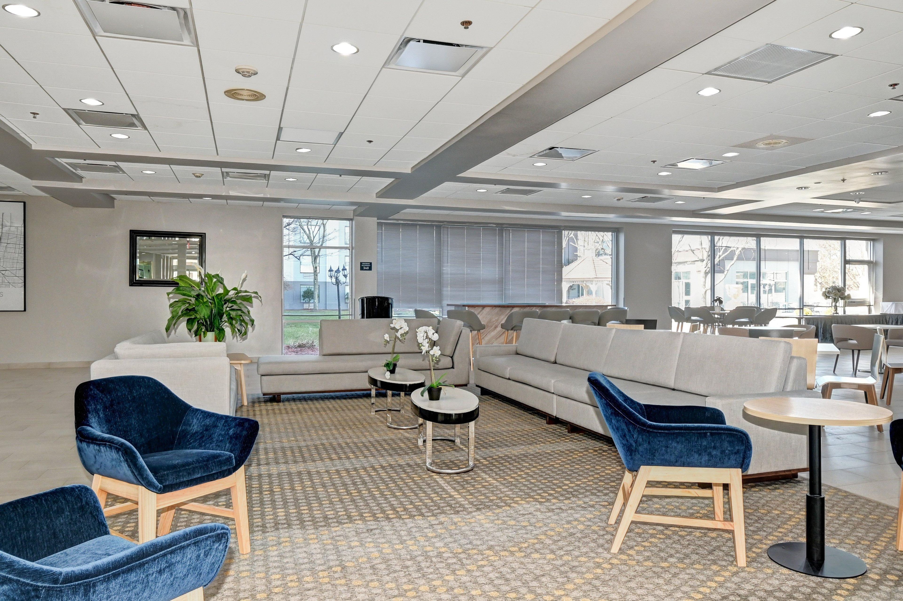 A spacious lounge area with sofas, chairs, and a patterned carpet.