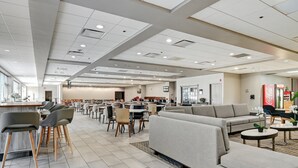 Un amplio vestíbulo de hotel con una zona de bar, asientos y un gran sofá.