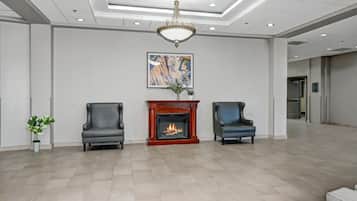 A spacious lobby with a fireplace, two leather chairs, a chandelier, and a modern painting on the wall.