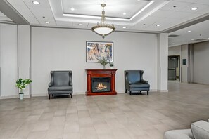 A spacious lobby with a fireplace, two leather chairs, a chandelier, and a modern painting on the wall. - Holiday Inn Piscataway - Somerset (Piscataway)