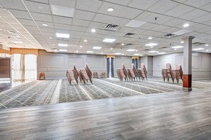Una vasta sala conferenze vuota, con file di sedie, una moquette decorata e un soffitto con faretti.