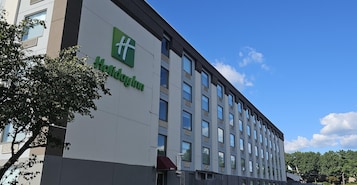 Edificio de un hotel Holiday Inn con fachada moderna, ventanas amplias y cielo despejado.