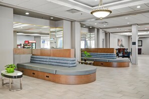 A modern lobby with seating areas, a reception desk, and a large mirror reflecting the space. - Holiday Inn Piscataway - Somerset (Piscataway)