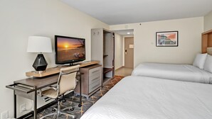 Habitación de hotel con cama, escritorio, silla, televisor y obras de arte.