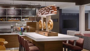 Zona de bar moderna con mostrador de madera, asientos y una pizarra de menú.