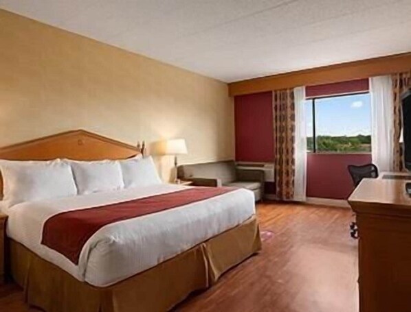 Une chambre d’hôtel avec un grand lit, un bureau et une vue sur l’extérieur.