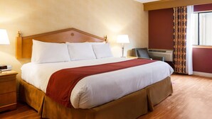 A neatly made bed with a wooden headboard, a red throw blanket, and two bedside lamps. - Toms River (Toms River)