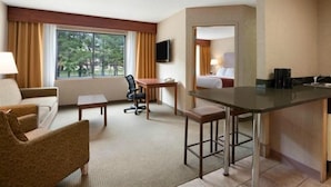 A hotel room with a desk, a chair, a sofa, a bed, a TV, and a kitchenette. - Toms River (Toms River)