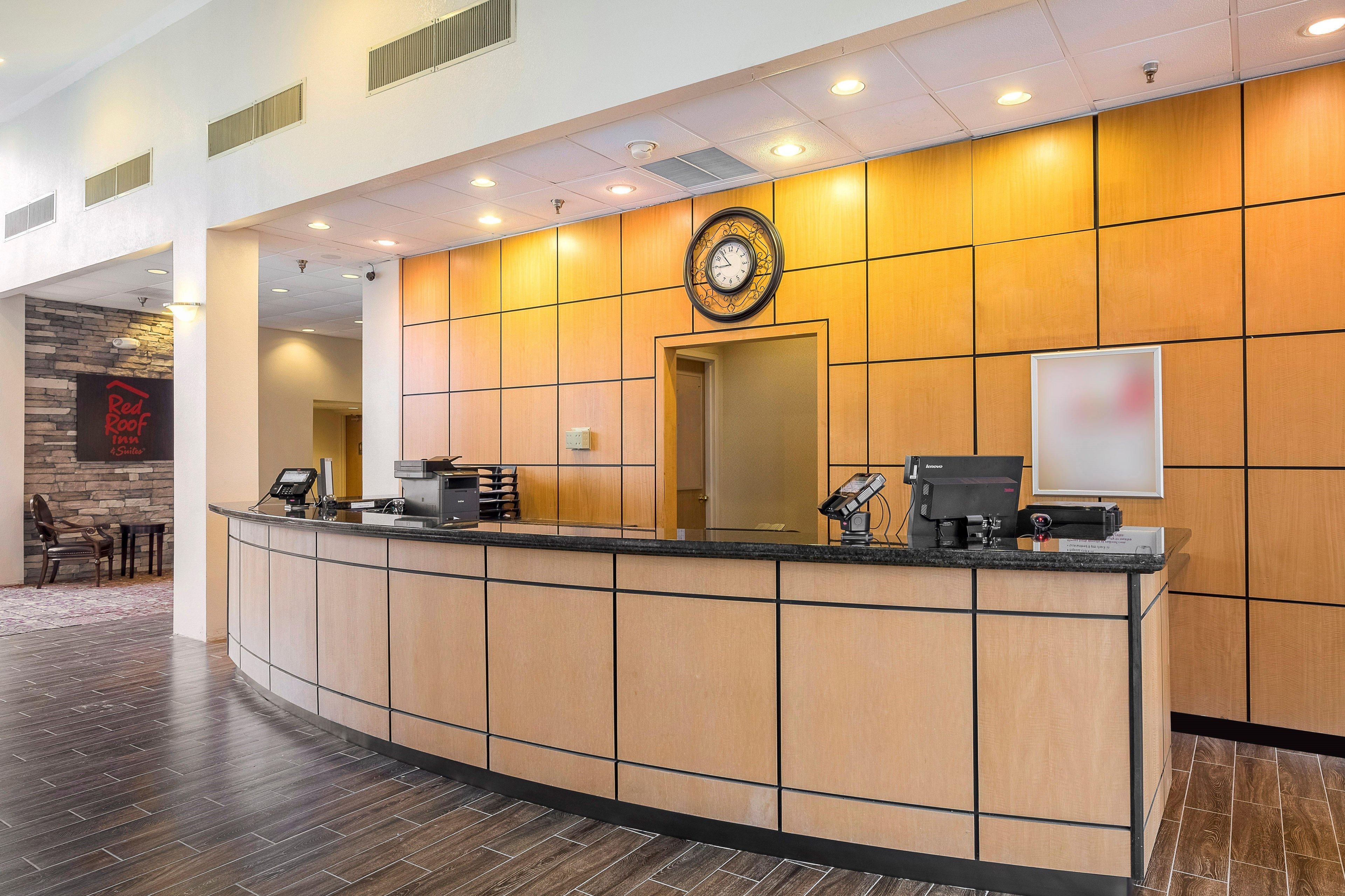 A hotel reception desk with a clock, a digital screen, and a reception counter.