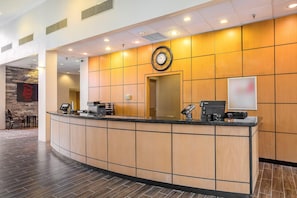 Taulell de recepció d'hotel amb rellotge, pantalla digital i mostrador.