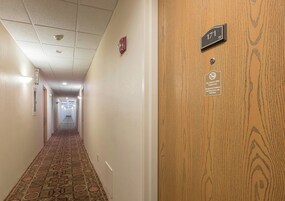 A hotel hallway with a fire extinguisher sign, a smoke detector, and a smoke-free sign on the door.