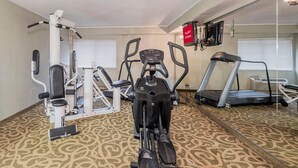 A gym with exercise equipment, a treadmill, and a mirror reflecting the room.