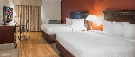 Habitación de hotel con dos camas, un escritorio con televisor, una silla, una lámpara y una ventana con cortinas.