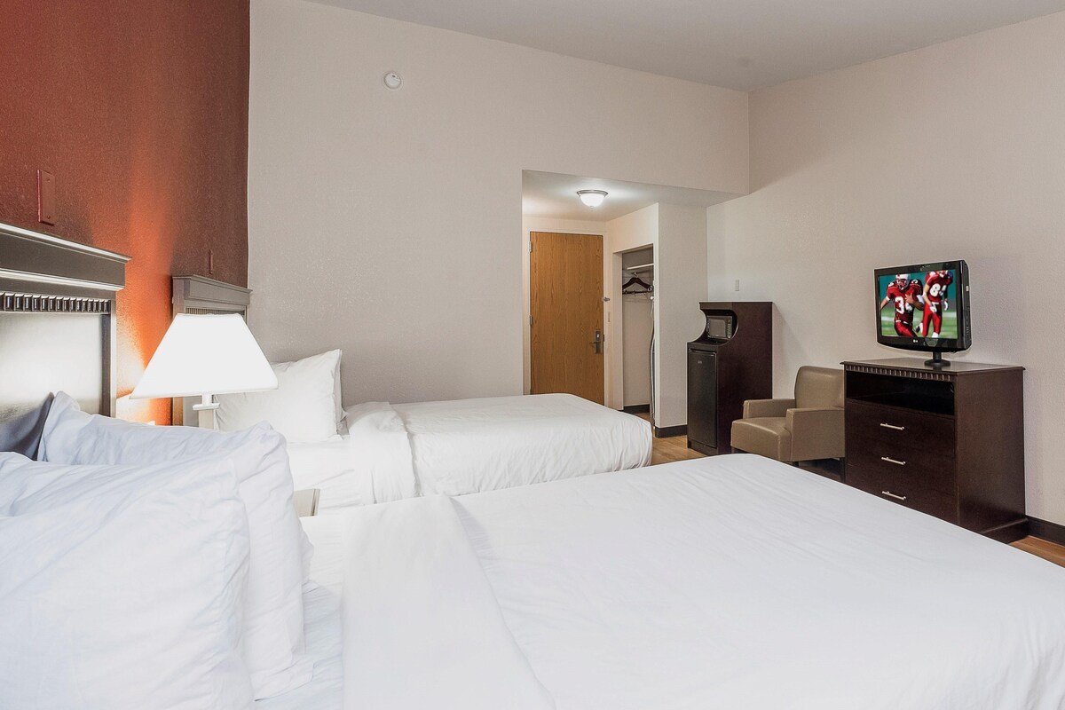 A hotel room with two beds, a television, a desk, and a wardrobe.