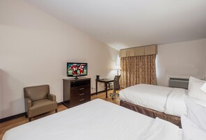 Habitación de hotel con dos camas, televisión, escritorio, silla y ventana con cortinas.