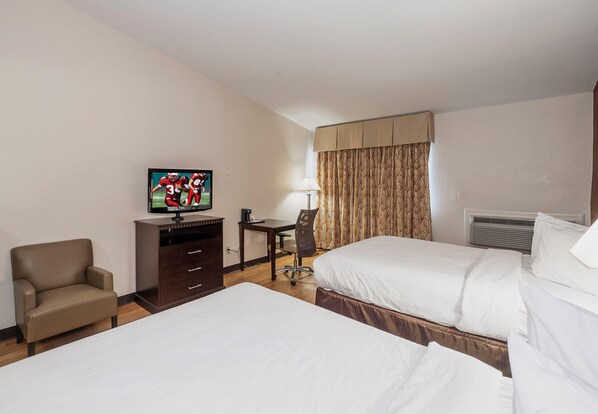Hotelkamer met twee bedden, een bureau, een stoel, een televisie en een raam met gordijnen.