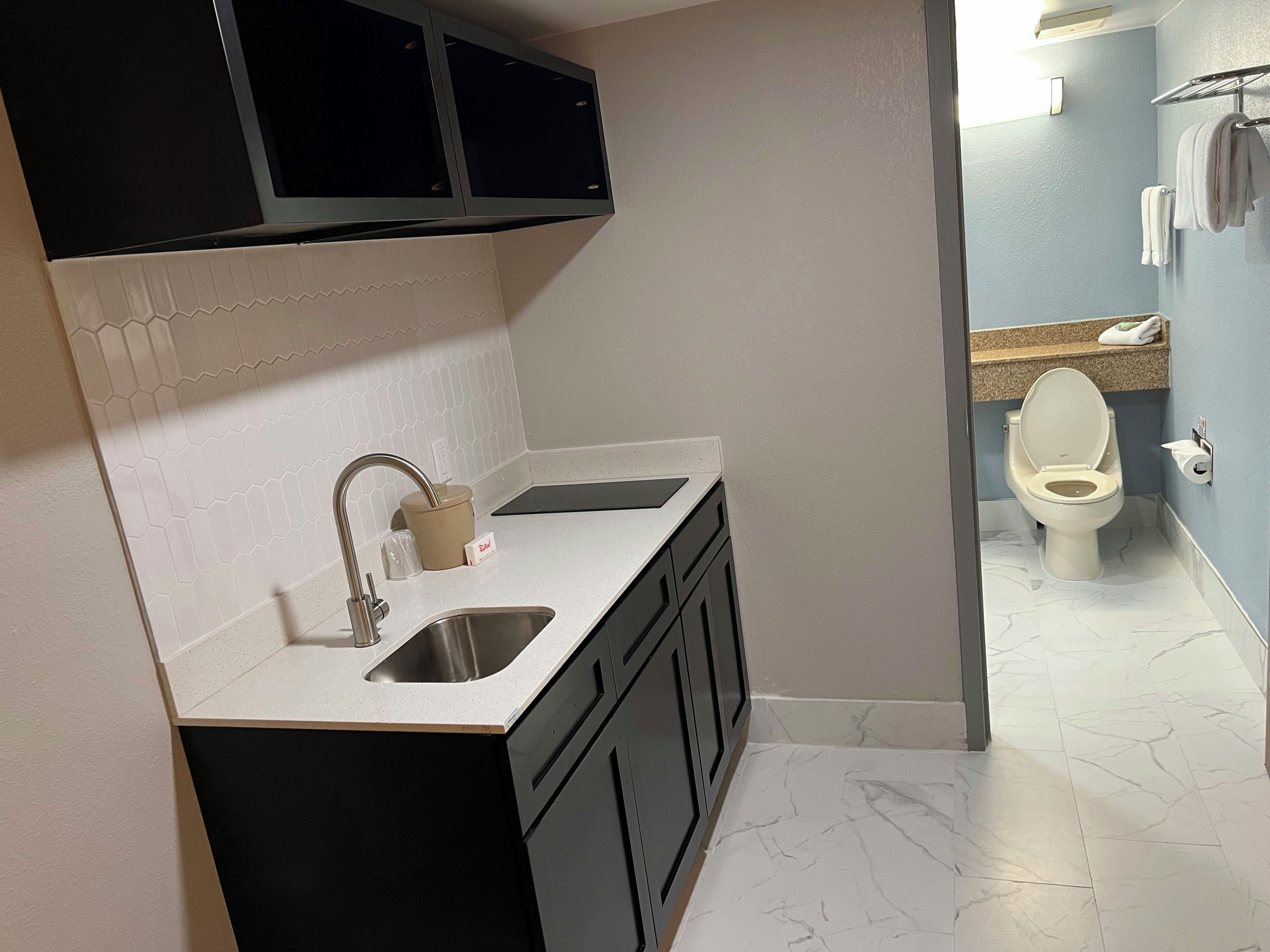 Une petite salle de bain comprenant des toilettes, un lavabo et des placards de rangement.