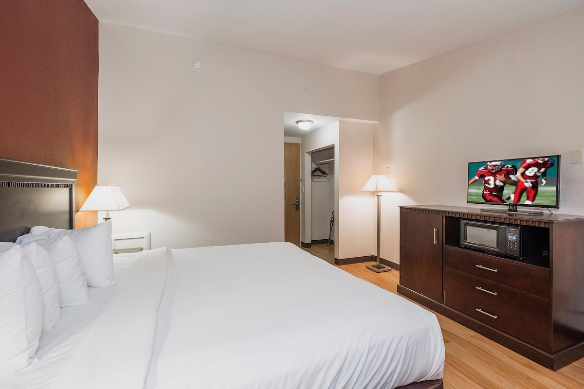 A hotel room with a bed, a TV, a microwave, and a wardrobe.