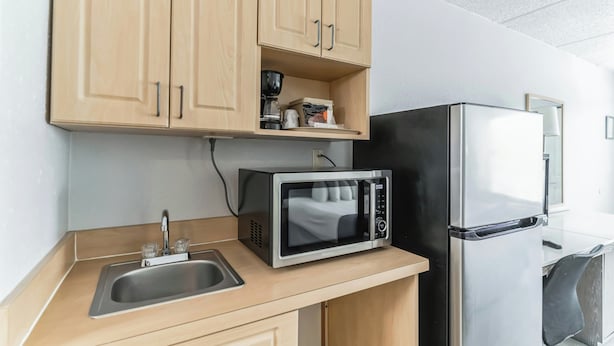 Eine Küchenzeile mit Mikrowelle, Kühlschrank, Spüle und Holzausstattung.