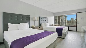 Ein Hotelzimmer mit zwei Betten, einem großen Fenster und einer Tür.