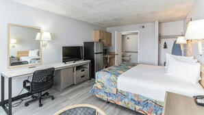 Ein Hotelzimmer mit Bett, Schreibtisch, Stuhl, Fernseher, Kühlschrank und Badezimmer.