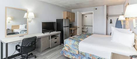 A hotel room with a bed, desk, chair, television, refrigerator, and a bathroom.