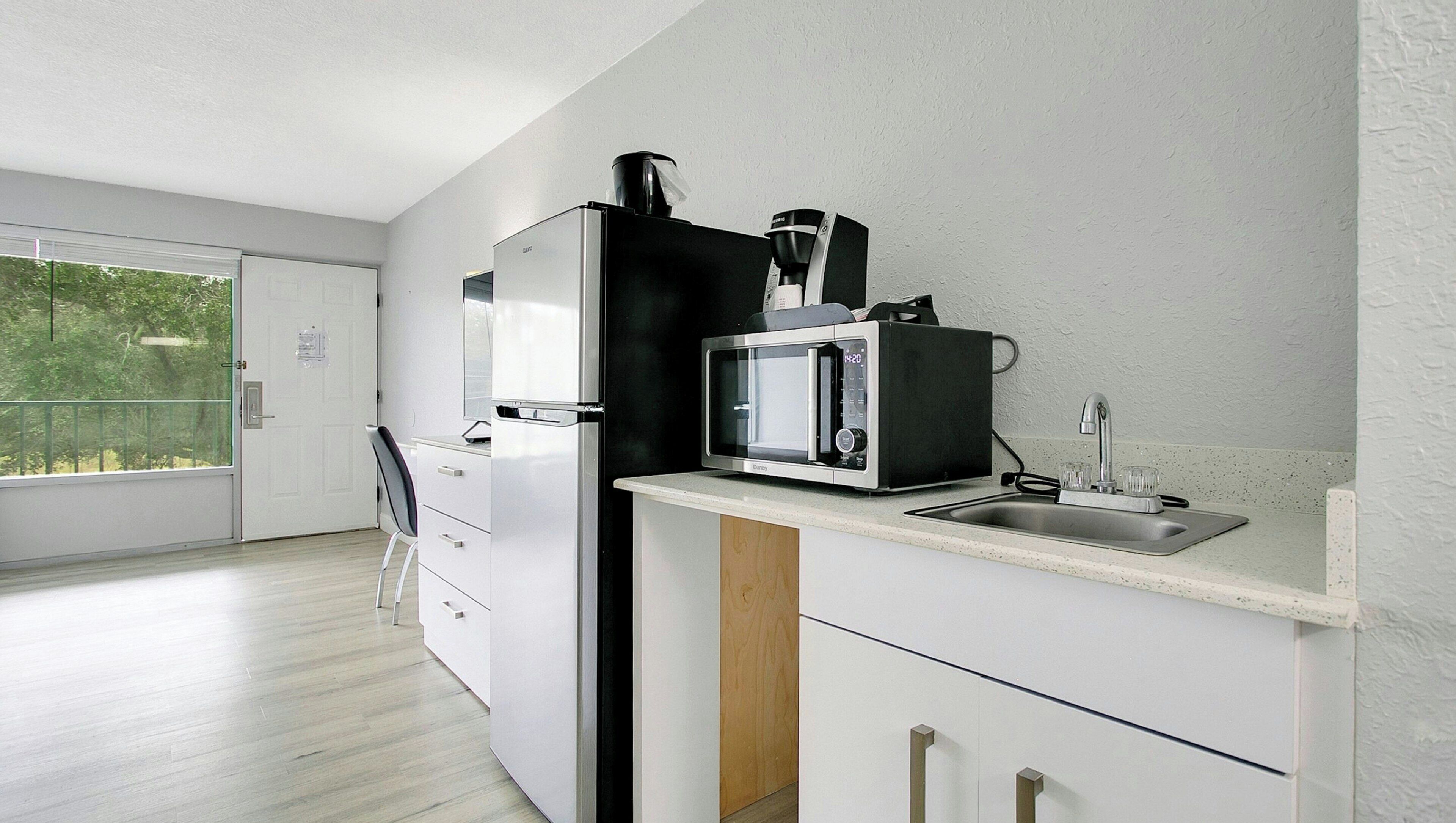 Una cocina moderna con microondas, cafetera y lavamanos.