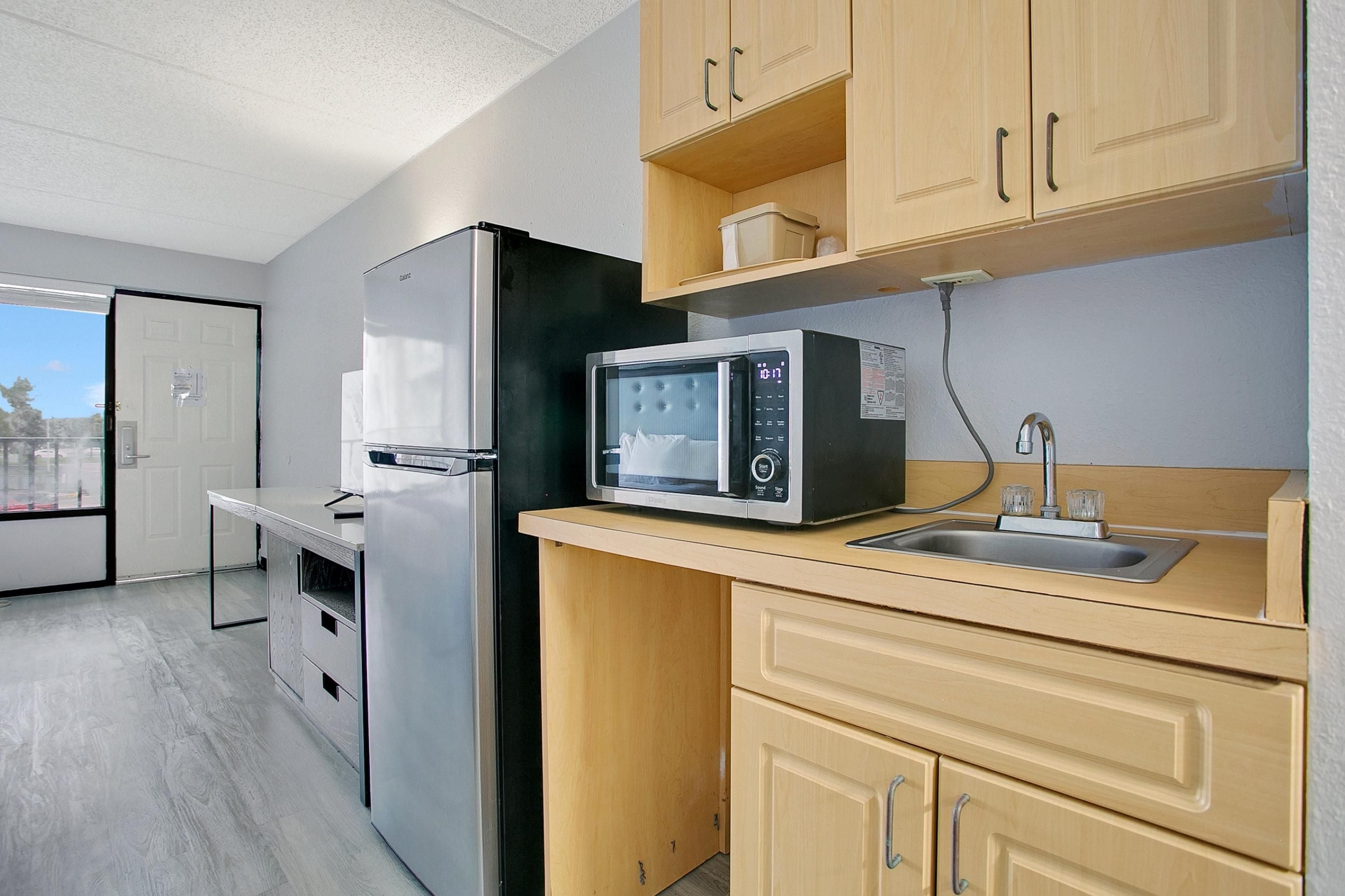 A compact kitchen with a refrigerator, microwave, and sink.