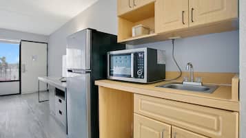 Cocina compacta con refrigerador, microondas y lavamanos.