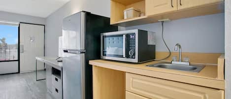 A compact kitchen with a refrigerator, microwave, and sink.
