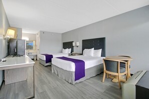 A hotel room with two beds, a desk, a chair, and a small table. - Home 1 Suites Extended Stay - Kissimmee (Kissimmee)