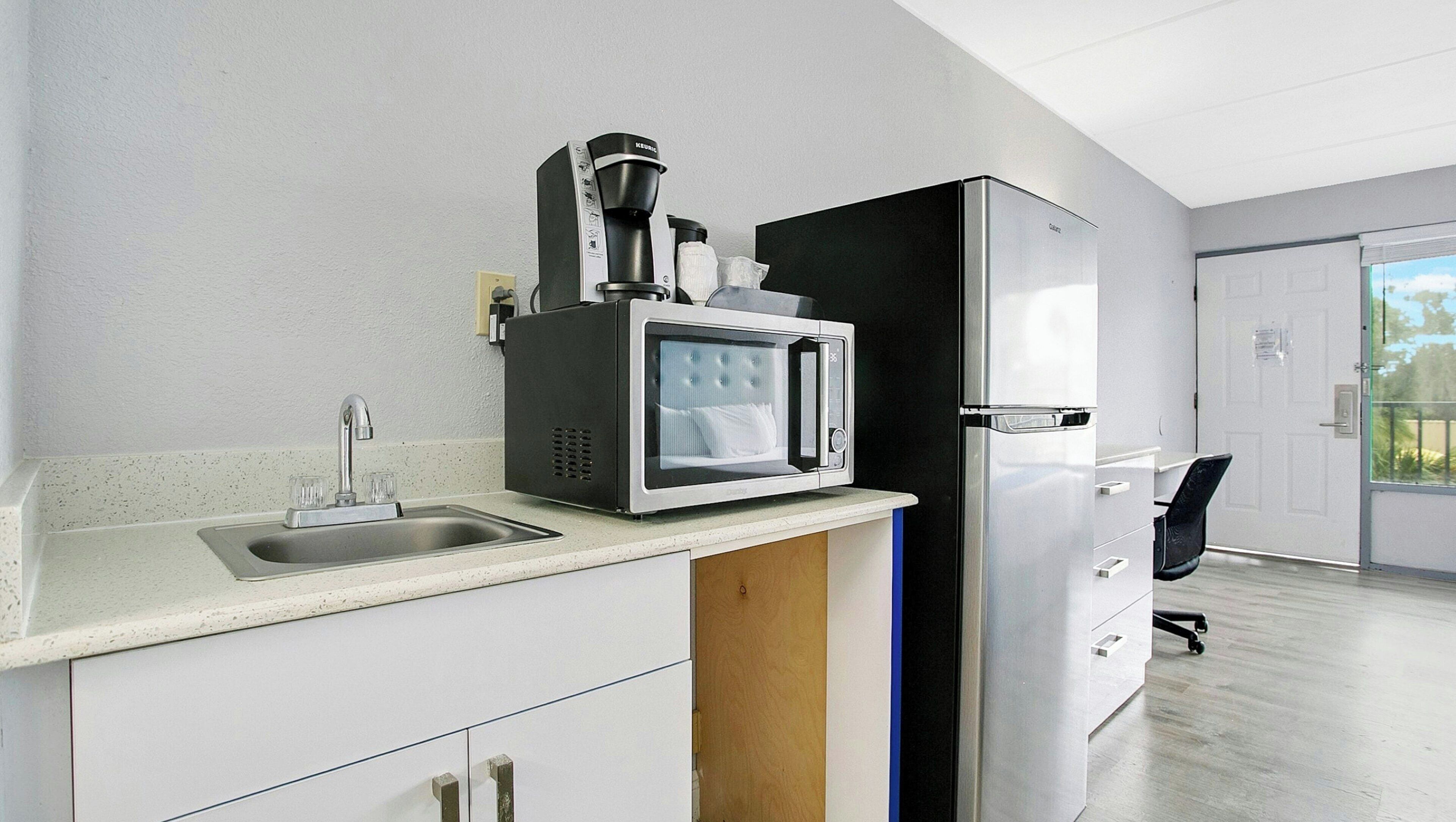 A modern kitchen with a coffee maker, microwave, and refrigerator.