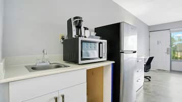 A modern kitchen with a coffee maker, microwave, and refrigerator.