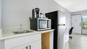 A modern kitchen with a coffee maker, microwave, and refrigerator. - Home 1 Suites Extended Stay - Kissimmee (Kissimmee)