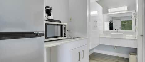 Une cuisine moderne équipée d’un four à micro-ondes encastré, d’une machine à café et d’un évier.