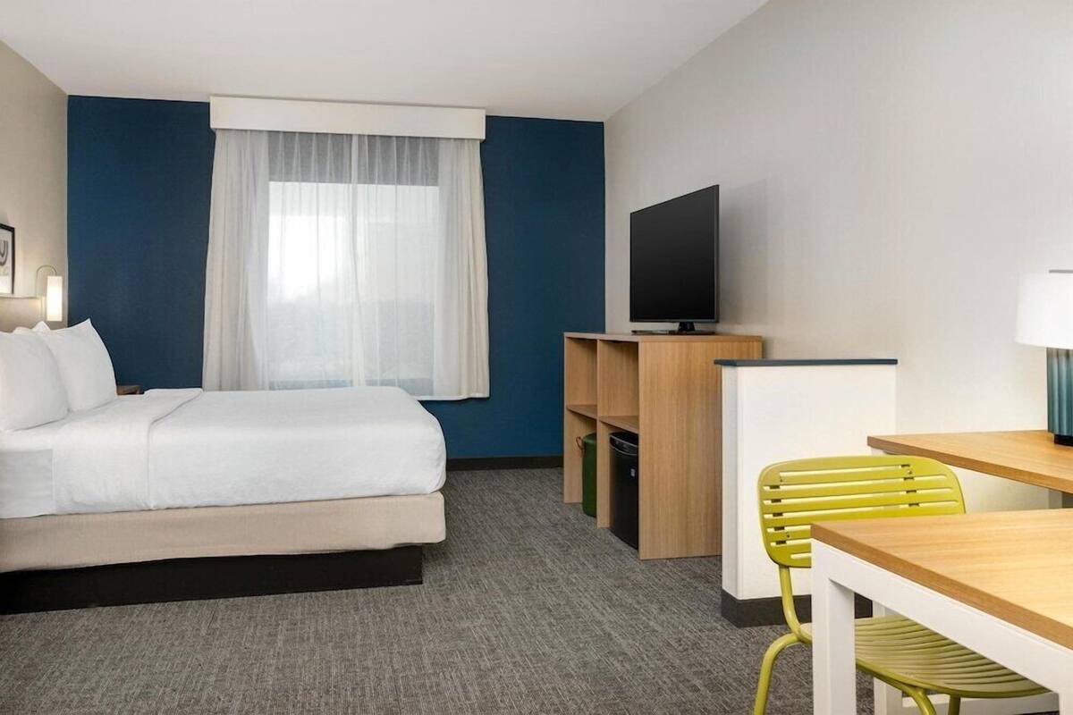 A hotel room with a bed, a television, a desk, and a chair.