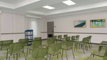 Ein Konferenzraum mit grünem Stuhlkreis, einem blauen Tisch und zwei abstrakten Bildern an der Wand.