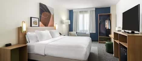 Camera d'albergo con un letto grande, un armadio, una televisione e una scrivania.