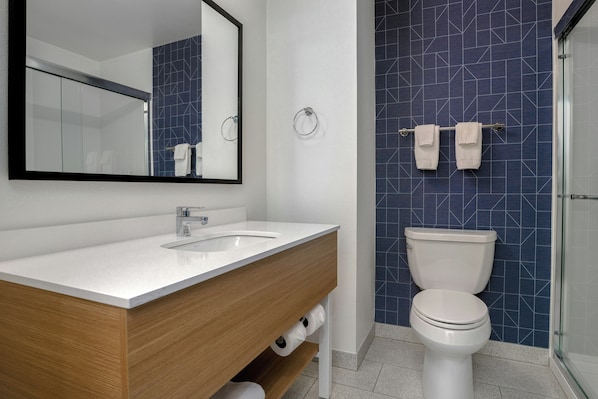 Une salle de bain moderne avec un lavabo blanc, un meuble-lavabo en bois, des toilettes et une cabine de douche en verre.