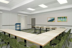 A conference room with a long table, green chairs, and two abstract paintings on the wall. - Spark by Hilton Rahway (Rahway)