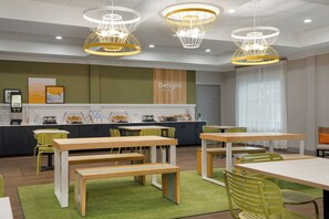 A modern cafe interior with multiple tables and chairs, a kitchen area, and a sign that reads 'Delight in the day.' - Spark by Hilton Rahway (Rahway)
