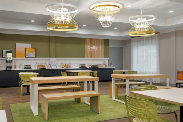 A modern cafe interior with multiple tables and chairs, a kitchen area, and a sign that reads 'Delight in the day.'