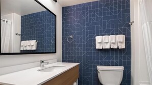 Un baño con un lavabo blanco, un espejo, un inodoro y baldosas azules con diseño.