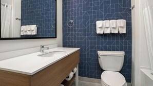 Un baño con un lavabo blanco, un espejo, un inodoro y azulejos azules estampados.