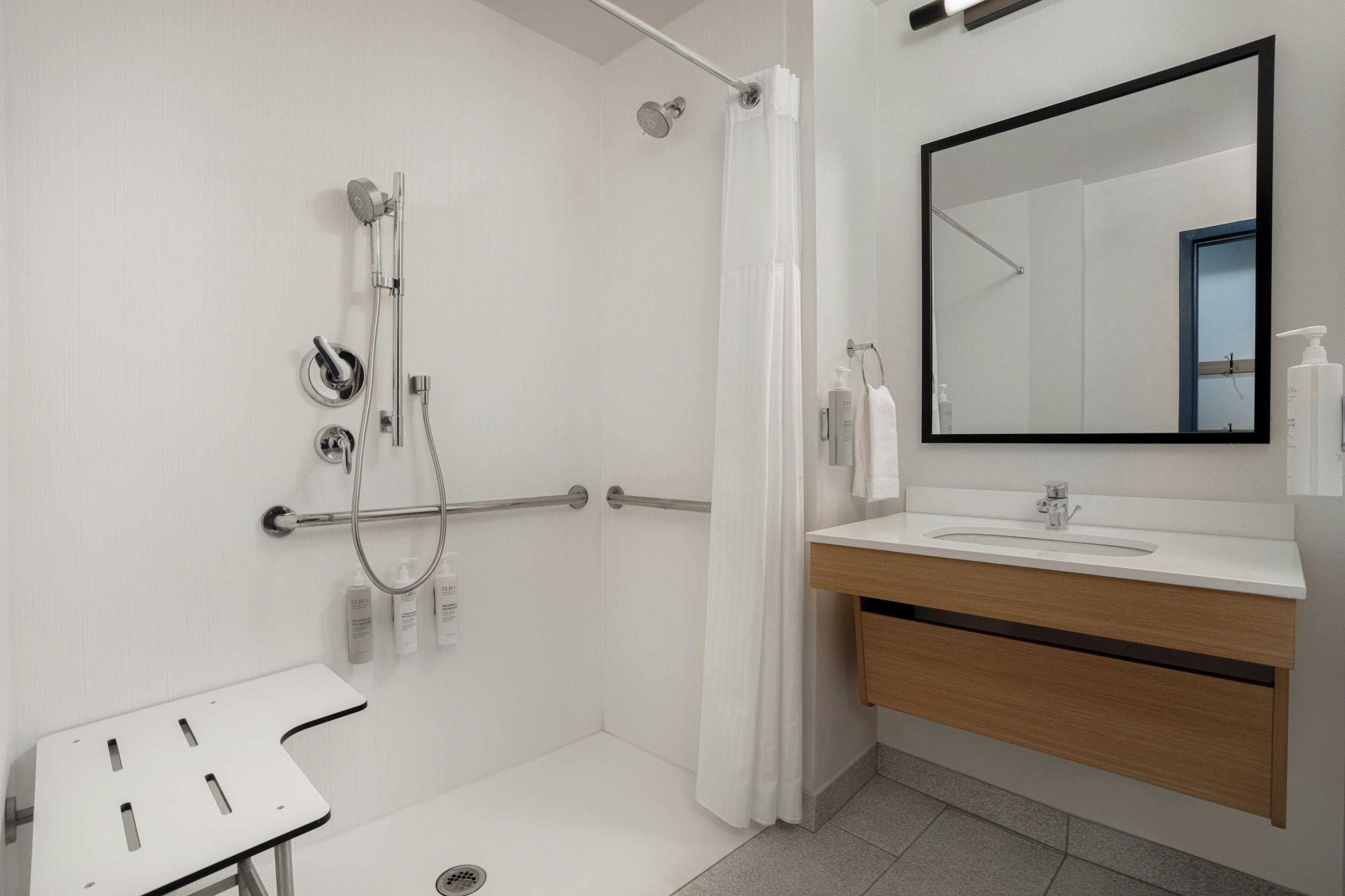 Un baño moderno con ducha, lavamanos, espejo y toallero.