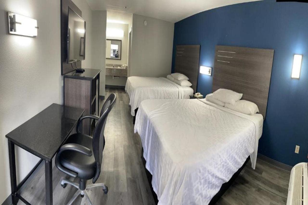 A hotel room with two beds, a desk, and a chair.