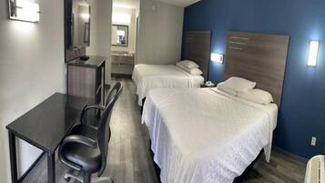 A hotel room with two beds, a desk, and a chair.