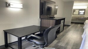 A hotel room with a desk, chair, TV, and a bed. - Griffin Inn & Suites (Griffin)